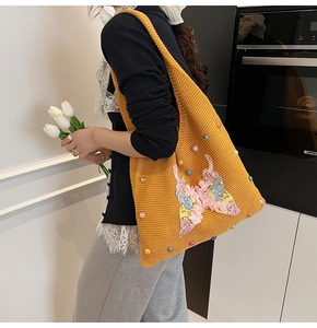 Detail of yellow knit shoulder bag featuring 3D butterfly embroidery and colorful beads
