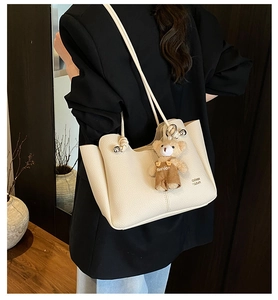 Close-up of off-white litchi grain tote bag with cute teddy bear charm on the side