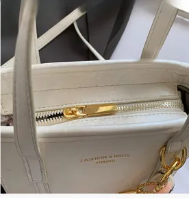 Close-up of smooth gold metal zipper detail on white minimalist leather bucket bag