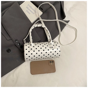 Macro shot of the white polka dot cylinder handbag with leather straps and silver hardware