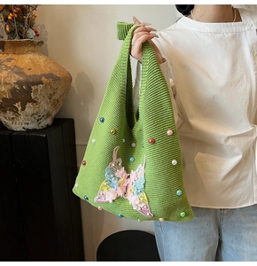 Close-up of green knit shoulder bag with colorful beads and a 3D mesh butterfly applique
