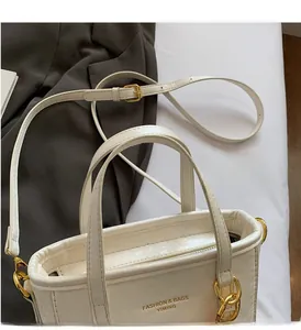 Detail of white litchi leather bucket bag with gold hardware and logo on a blazer background