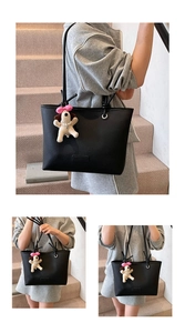 Detail of black pebbled leather tote bag with a cute white dog plush pendant and pink bow