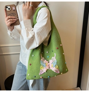 Detail of green knitted tote bag with colorful butterfly embroidery and beaded accents