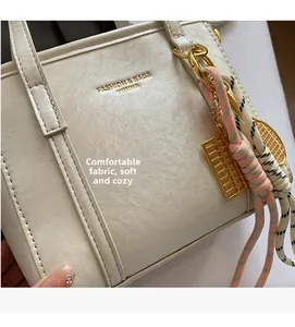Close-up of cream leather bucket bag texture with gold abacus charm and braided rope