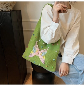 Detail of green woven tote bag with 3D butterfly appliqué and colorful bead accents