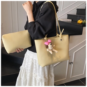 Detail of cream pebble leather tote set with small pouch and plush puppy charm