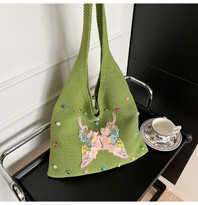 Detail of green knit tote bag featuring colorful 3D butterfly embroidery and beads