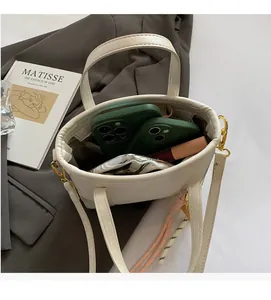 Top view of cream leather bucket bag interior showing spacious storage with phones and lipstick