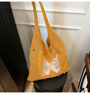Close-up of yellow knit hobo bag featuring 3D butterfly appliques and colorful beads