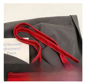Close-up of red canvas tote bag showing white contrast stitching on handle and seam