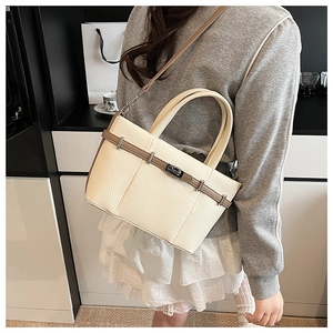 Détail du sac seau en cuir beige grainé avec bandoulière marron et fermoir argenté