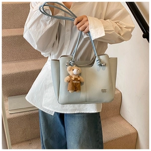 Detail of light blue lychee pattern tote bag with cute bear charm and silver buckle