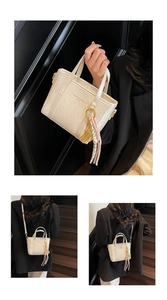 Close-up of creamy white textured bucket bag with golden hardware and fringe tassel detail