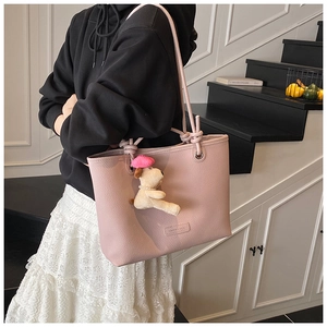 Pink lychee grain leather tote bag with cute puppy plush charm on model shoulder