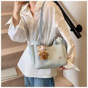 Close-up of light blue lychee pattern leather tote bag with a cute bear plush charm