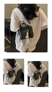 Close-up of black bucket bag with textured leather finish and silk scarf detail