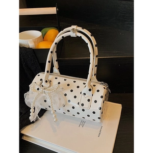 Chic white cylinder bag with black polka dots featuring pearl bow and lace charm
