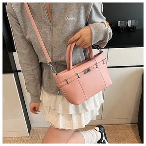 Détail de la texture cuir litchi rose avec boucle argentée sur un sac seau élégant