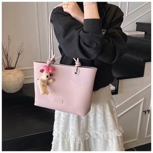 Pink lychee texture tote bag detail with plush dog pendant and tied rope shoulder strap
