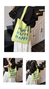 Detail of green canvas tote bag with blue HAPPY HAPPY HAPPY text on a white lifestyle background