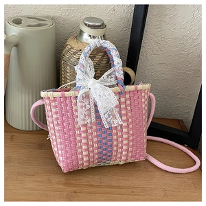Détail du sac tissé rose et blanc avec un nœud en dentelle blanche et bandoulière corde