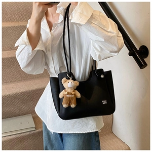 Close-up of black lychee texture tote bag with a cute brown plush bear charm detail