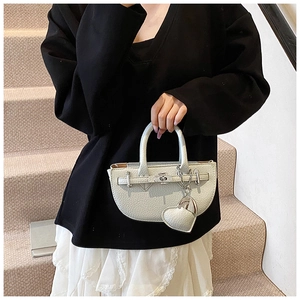 Close-up of a white lychee grain mini semi-circular handbag with silver hardware and heart charm