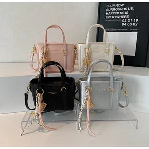Detail view of four leather bucket bags in pink, white, black, and silver finishes