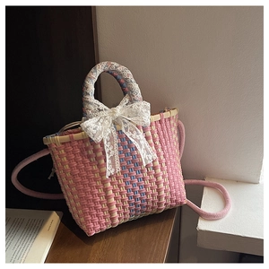 Détail du sac à main tissé rose avec nœud en dentelle blanche et poignée fleurie