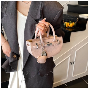 Detail of light pink lychee texture semi-circle handbag with silver clasp and heart charm