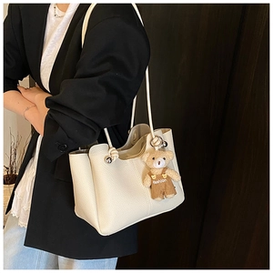 Detail of off-white lychee texture tote bag with a cute bear charm and metal buckle