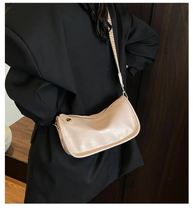 Détail d'un sac bandoulière incurvé beige clair avec large bandoulière tissée décorative