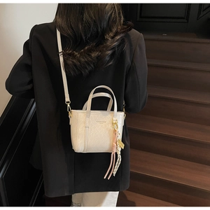 Detailed macro view of beige leather bucket bag with silk scarf and tassel accents