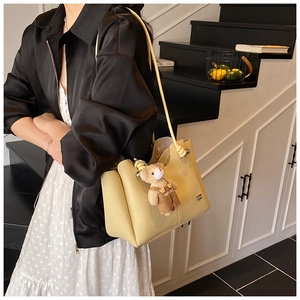 Detail of lychee pattern leather tote bag with a cute bear charm and metal buckle