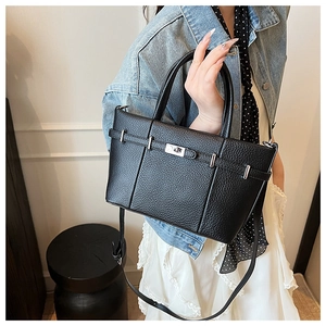 Vue détaillée du sac seau noir en cuir grainé avec fermoir rotatif argenté et bandoulière