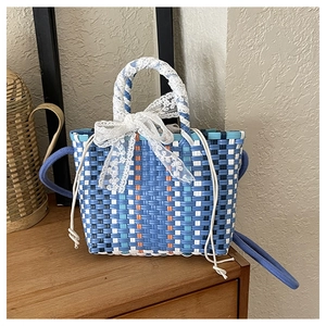 Détail du panier tressé à la main avec rayures bleues et blanches et nœud en dentelle