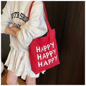 Detail of red canvas tote bag with bold Happy Happy letters and long shoulder straps