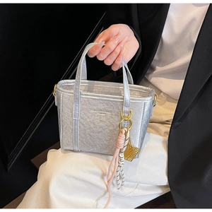 Detailed macro view of silver metallic pleated texture with brand lettering on a bucket bag