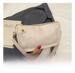 Détail d'un sac en cuir blanc crème avec une large bandoulière jacquard et ferrures rétro