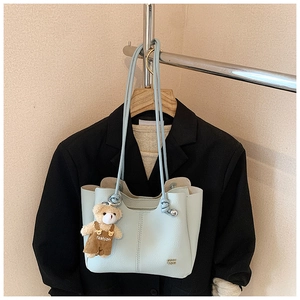 Detail of light blue lychee pattern leather tote bag with a cute teddy bear charm