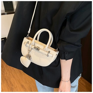 Detail of off-white lychee texture semicircular handbag with silver lock and heart charm