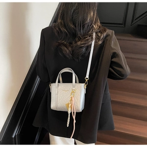 Detail of silver textured bucket bag with fashion print and silk scarf charm on shoulder strap