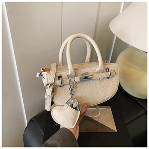 Detail of off-white lychee texture handbag with silver twist lock and heart charm