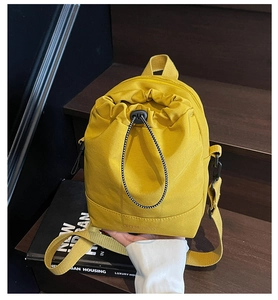 Detail of bright yellow canvas drawstring bag featuring branded logo on a book background