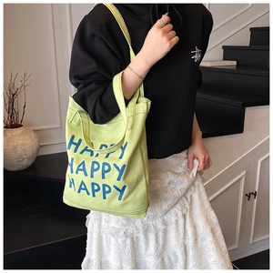 Close-up of lemon green canvas tote bag with bold blue Happy lettering for women