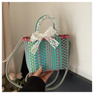 Détail d'un sac tressé multicolore avec un grand nœud en dentelle blanche et bandoulière