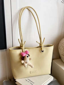 Minimalist pale yellow pebble leather tote bag with a cute plush puppy charm