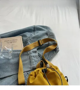 Detail of ginger yellow drawstring crossbody bag with pleated texture and adjustable strap