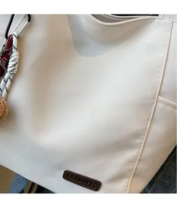 Detailed close-up of cream canvas tote bag with brown leather label and texture